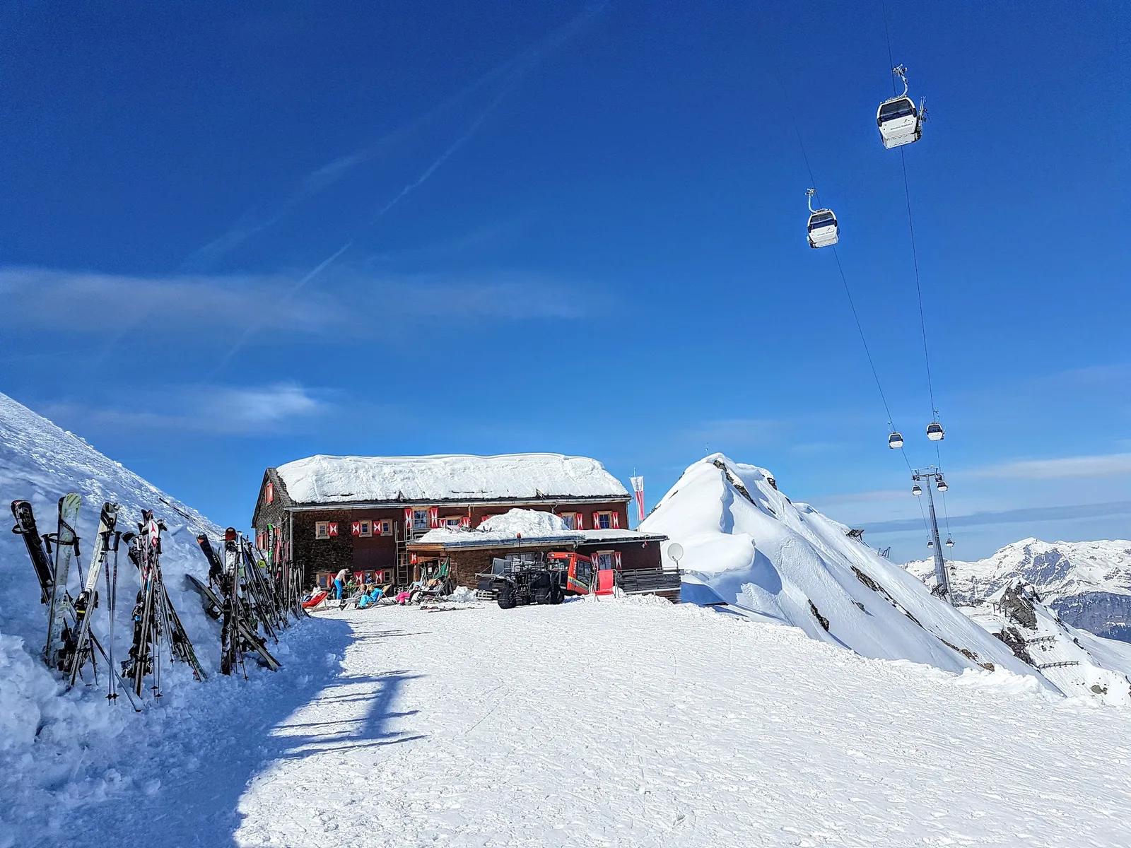 Die Wormser Hütte im Winter, davor aufgestellte Ski, darüber die Gondelbahn